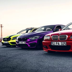 Tres coches o vehículos de alta gama aparcados en una carretera de asfalto