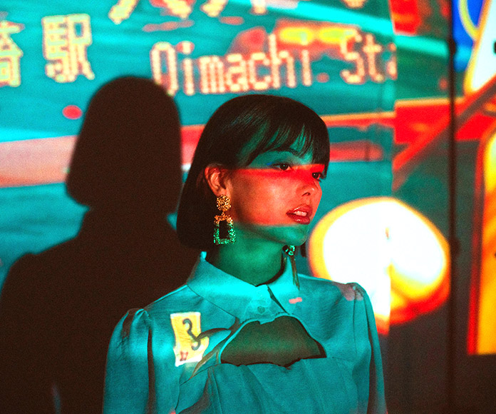 Mujer modelo frente a pantalla led y a proyección de colores