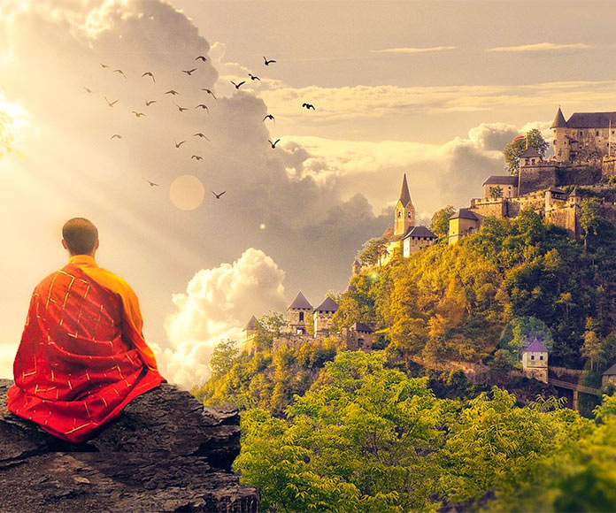 Monje budista meditando sentado en una roca mirando un paisaje de montañas y templo.